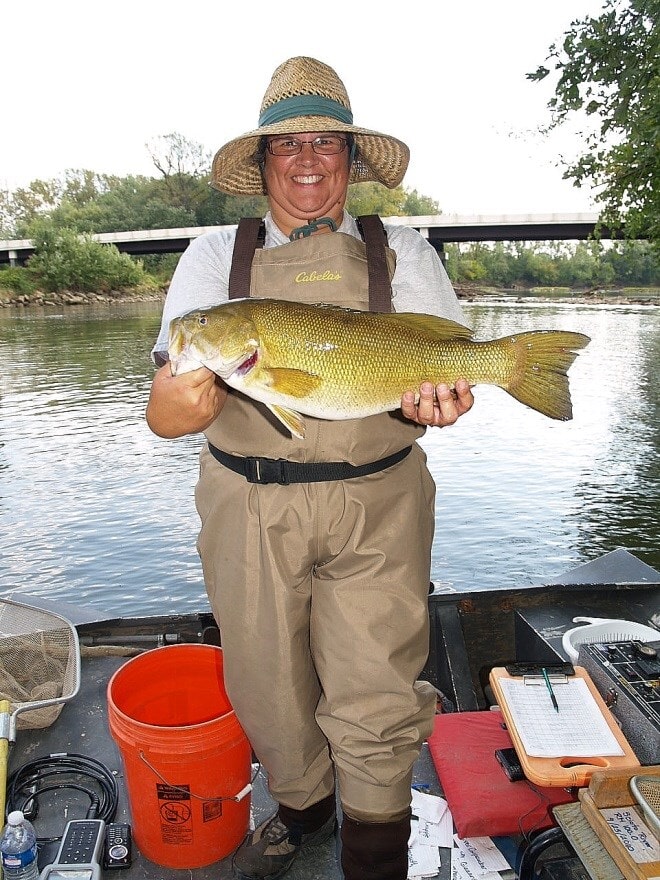 a woman holding a small mouth bass